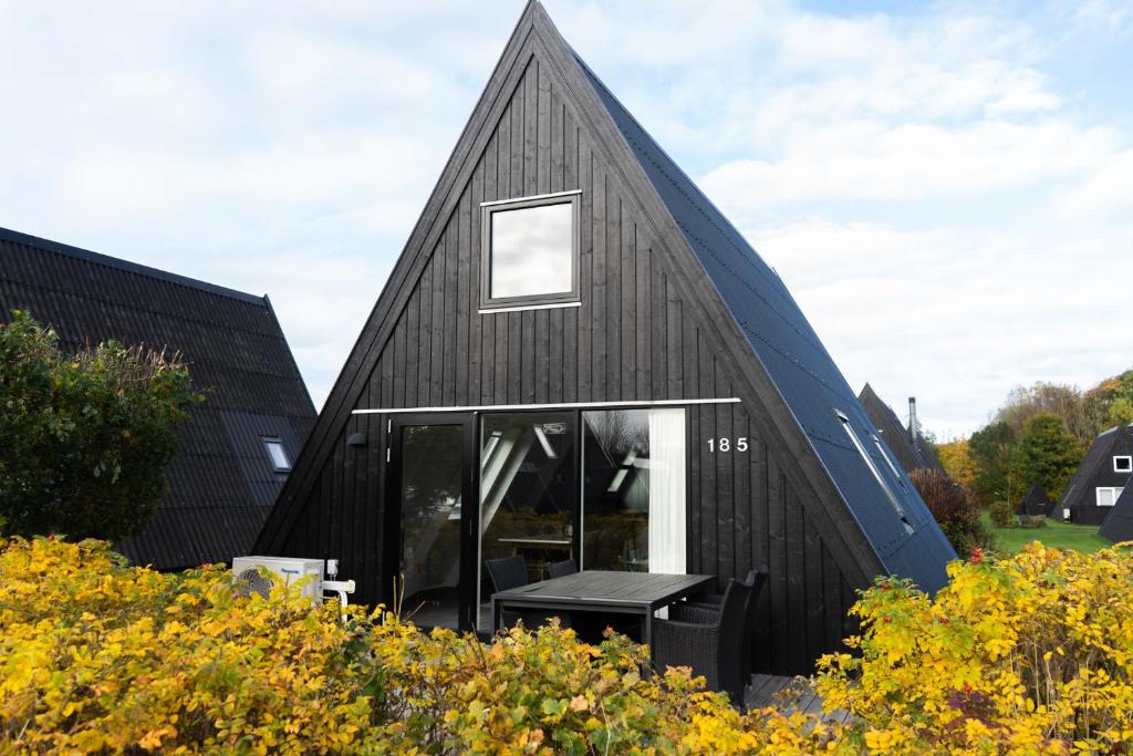 una casa negra con techo de gambrel en Himmerland Resort Cottages, en Farsø