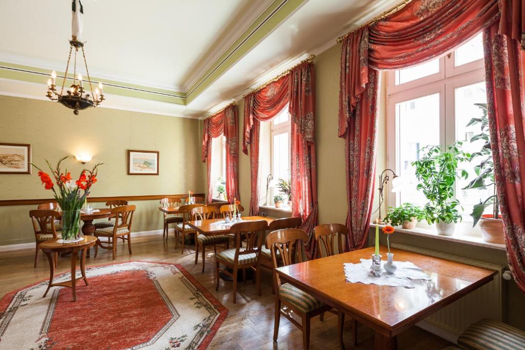 uma sala de jantar com mesas, cadeiras e janelas em Hotel Garni Schlossgarten em Neustrelitz