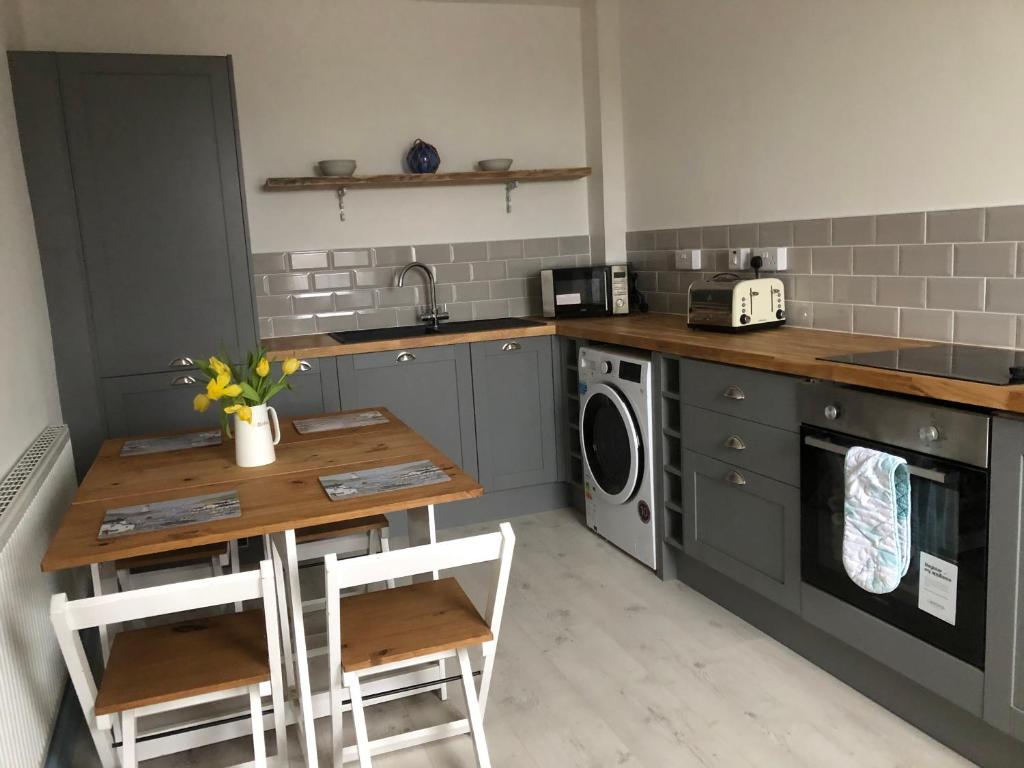 uma cozinha com uma mesa e uma máquina de lavar roupa em Graigfryn em Amlwch