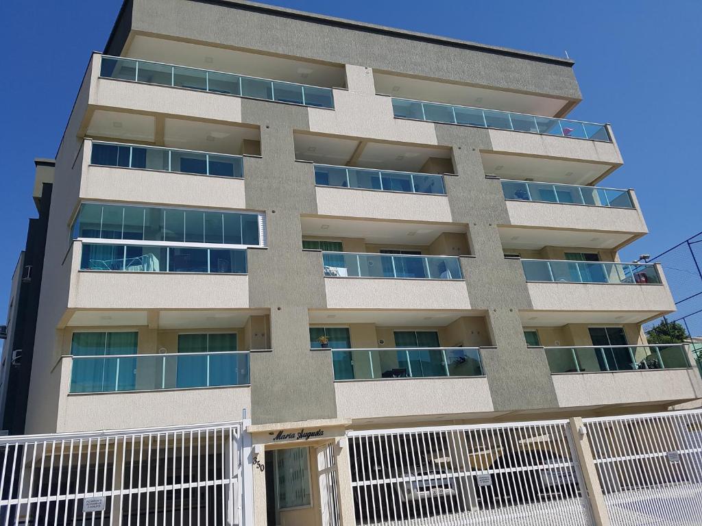 een appartementencomplex met een wit hek ervoor bij Apto Queen D'Arte Bombinhas in Bombinhas
