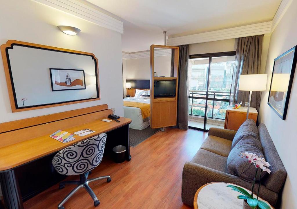 a hotel room with a desk and a bed at Estanplaza International in Sao Paulo