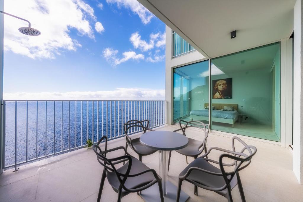 einen Balkon mit einem Tisch, Stühlen und Meerblick in der Unterkunft Barreirinha Front-Line Sea View I by HR Madeira in Funchal