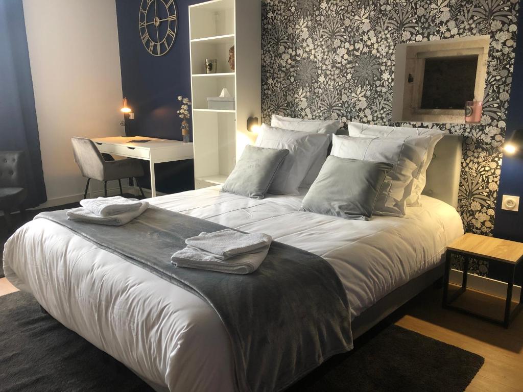 a bedroom with a large white bed with a desk at Hotel restaurant LA PLACE in Saint-Amand-Montrond