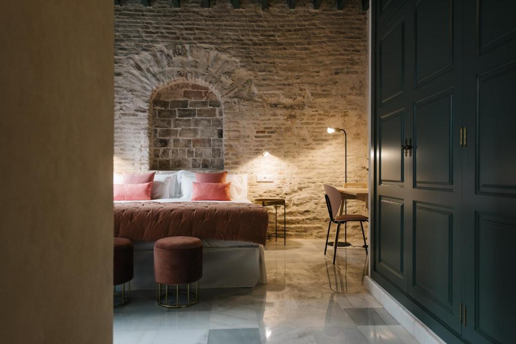 een slaapkamer met een bed en een bakstenen muur bij Magno Apartments Rocío in Sevilla
