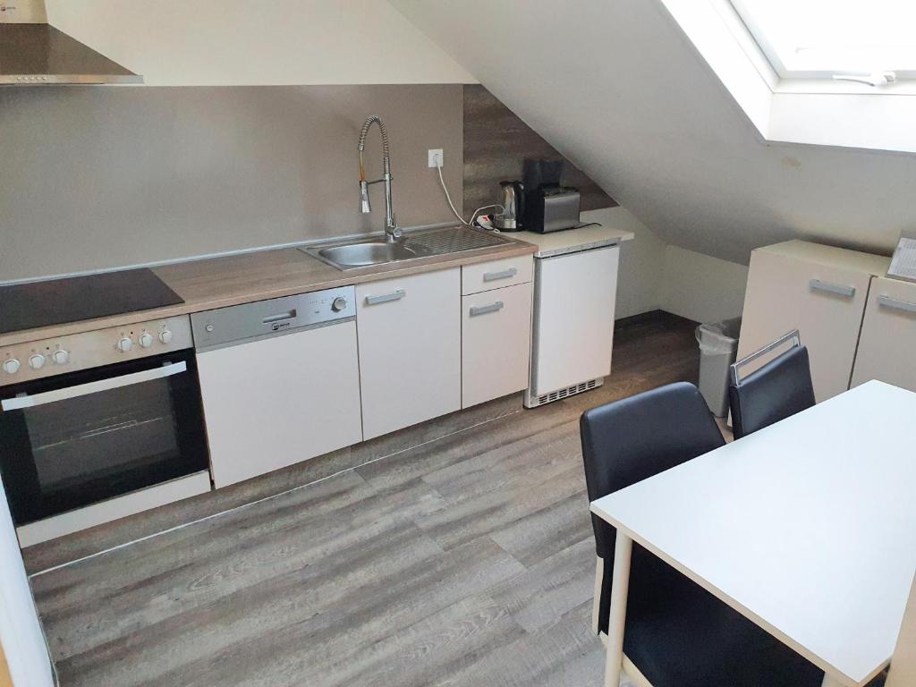 eine Küche mit weißen Schränken, einer Spüle und einem Tisch in der Unterkunft FMI44Apartment in Rüsselsheim