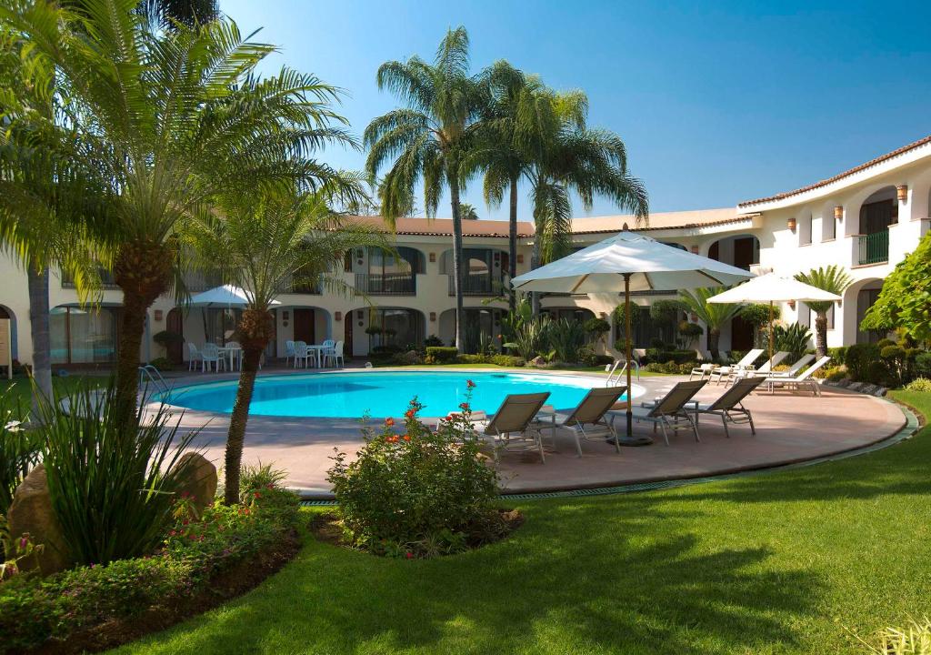 a resort with a swimming pool with chairs and umbrellas at Hotel Guadalajara Plaza Ejecutivo in Guadalajara