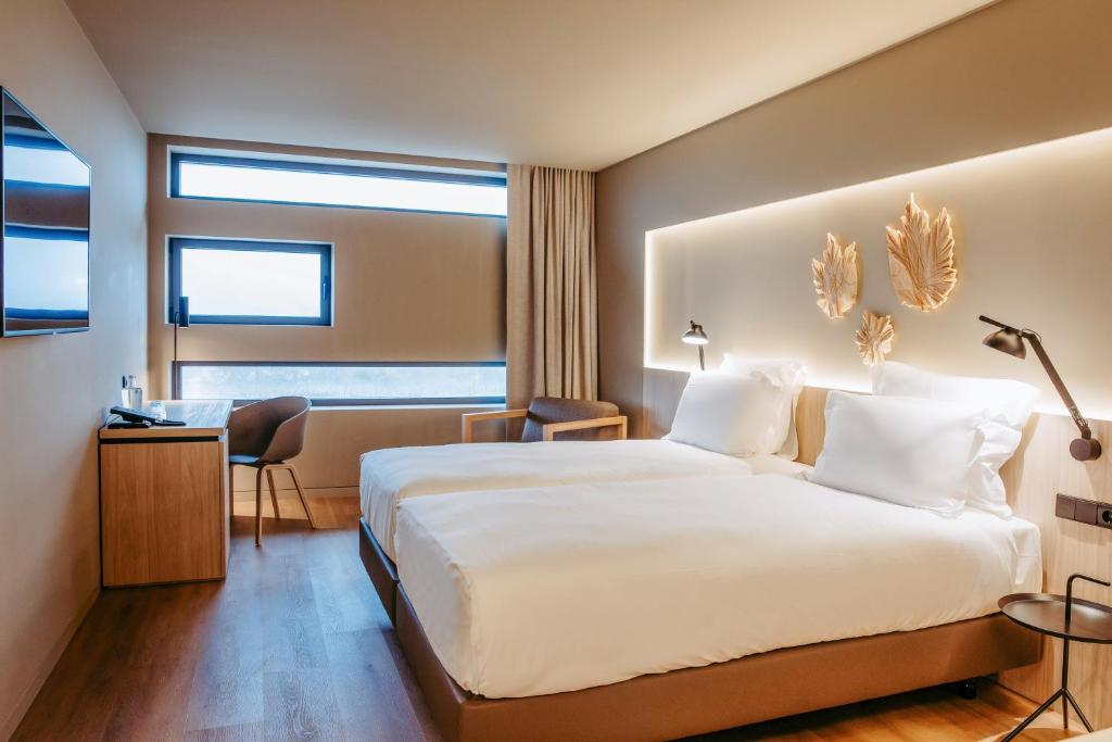 ファティマにあるMercure Fátimaの大きなベッドとデスクが備わるホテルルームです。