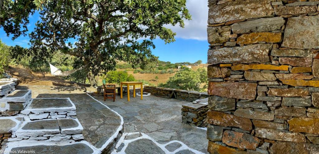 a stone walled patio with a table and chairs at Under Royal Oaks in Péra Meriá