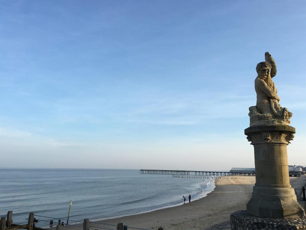 a statue on the beach with a pier in the background at Moray Beachside Apartments in Lowestoft