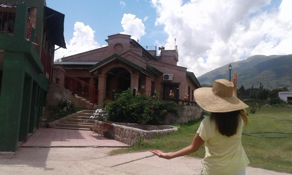 uma mulher de chapéu em frente a um edifício em HOSTERIA BUENAVISTA em Tafí del Valle