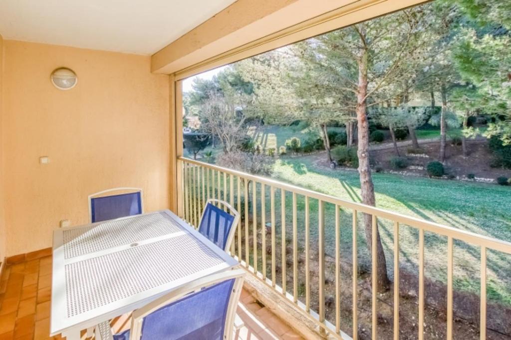 un balcon avec une table et des chaises et une grande fenêtre dans l'établissement Flat With Swimming Pool Near The Beach, à Sanary-sur-Mer