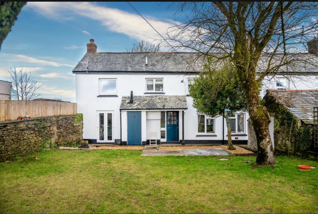 una casa blanca con una puerta azul y un patio en Finest Retreats - Court Cottage en East Buckland