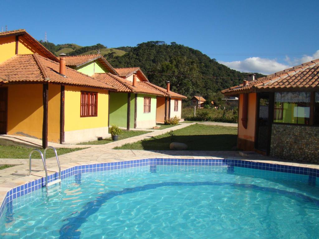 une piscine devant une maison dans l'établissement Pousada Chalés Vista da Serra, à Visconde de Mauá