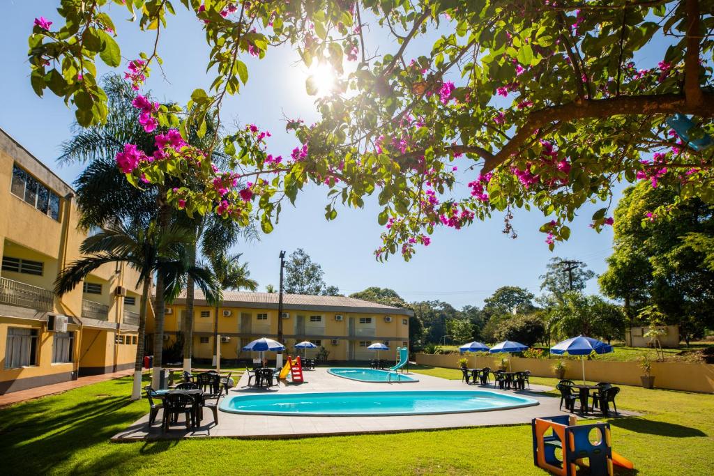 un cortile con piscina, tavoli e ombrelloni di Canzi Cataratas Hotel a Foz do Iguaçu