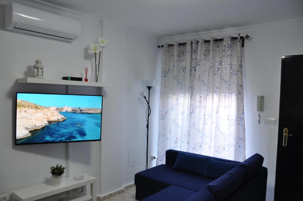- un salon avec un canapé bleu et une télévision murale dans l'établissement Villachipi, à Chipiona