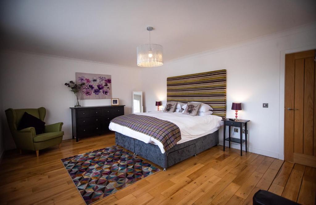 a bedroom with a large bed and a chair at Langley Cottage Retreat Sleeps 2 Long Stay 20-min to Banniskirk Hub in Wick
