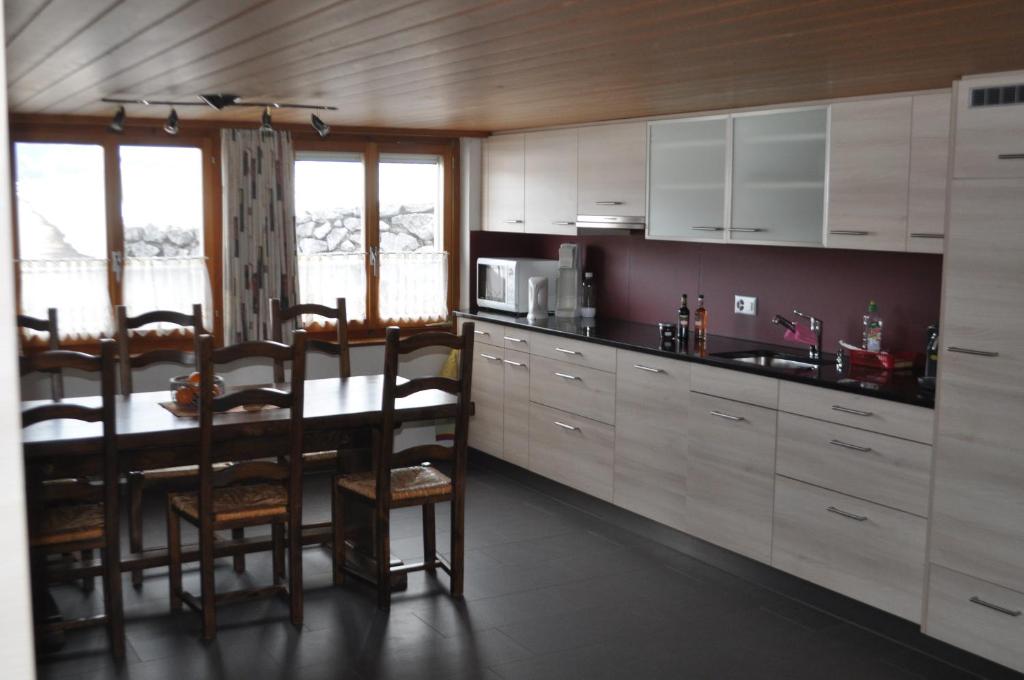 uma cozinha com armários brancos e uma mesa e cadeiras em Ruhe pur em Aeschi bei Spiez