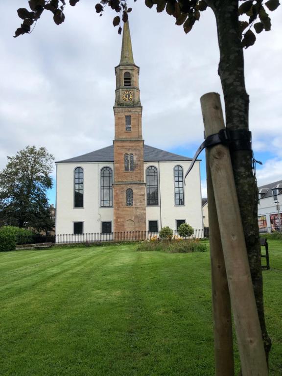 Una iglesia con una torre con un reloj. en East Church House, Unique 9 bedroom Church, Historic Market Town., en Strathaven