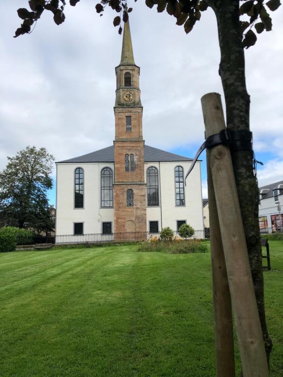 a church with a tower with a clock on it at East Church House, Unique 9 bedroom Church, Historic Market Town. in Strathaven