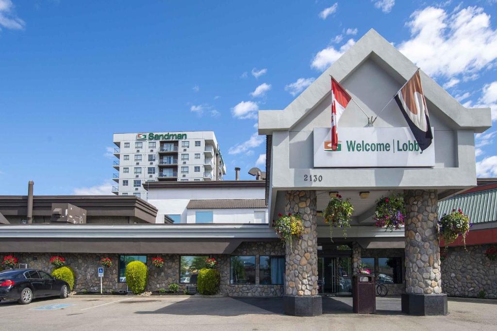 a building with a welcome sign on the front of it at Sandman Hotel & Suites Kelowna in Kelowna