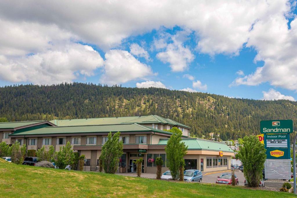 a large building with a mountain in the background at Sandman Hotel & Suites Williams Lake in Williams Lake