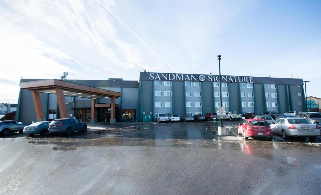 萊橋的住宿－Sandman Signature Lethbridge Lodge，停车场内停放汽车的大型建筑