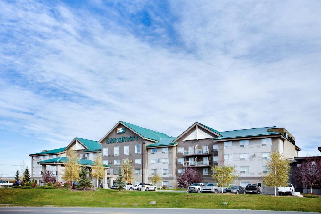 a large hotel with cars parked in front of it at Sandman Hotel & Suites Calgary West in Calgary