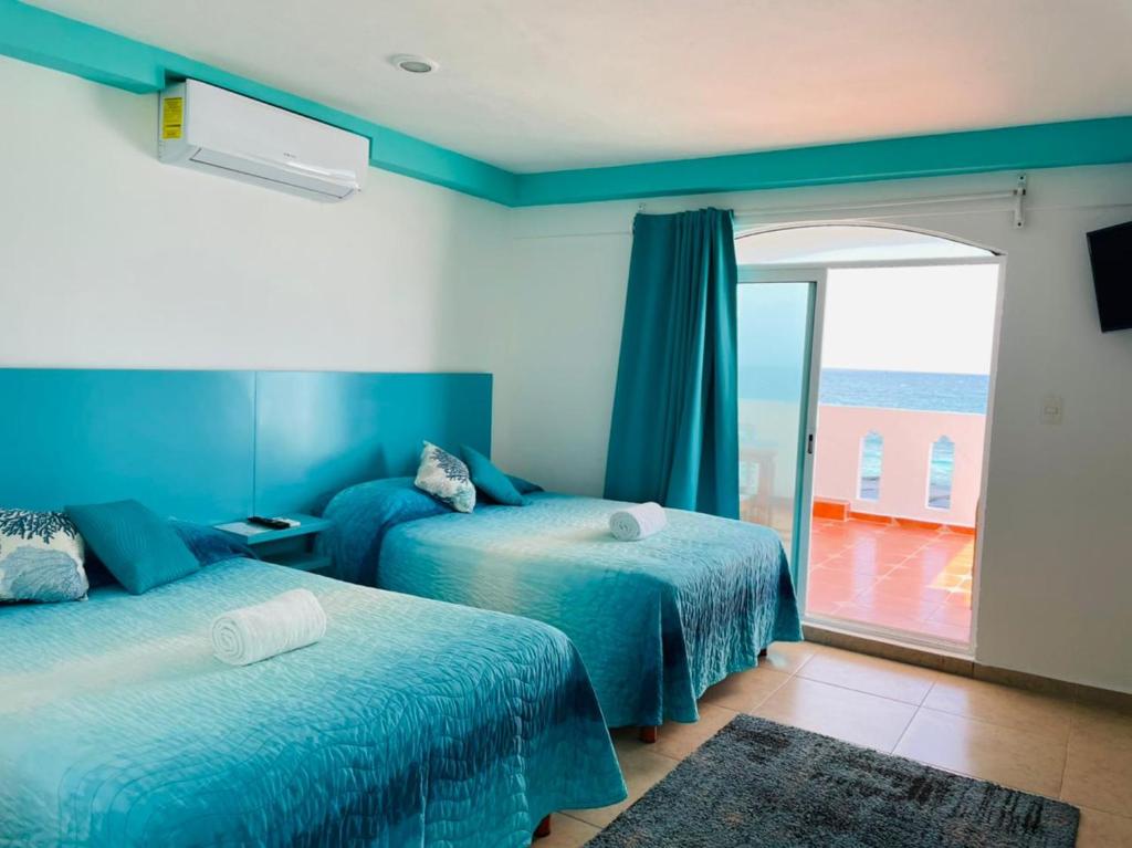 a bedroom with two beds and a balcony with the ocean at Habitación Amanecer Turquesa #2 in Isla Mujeres