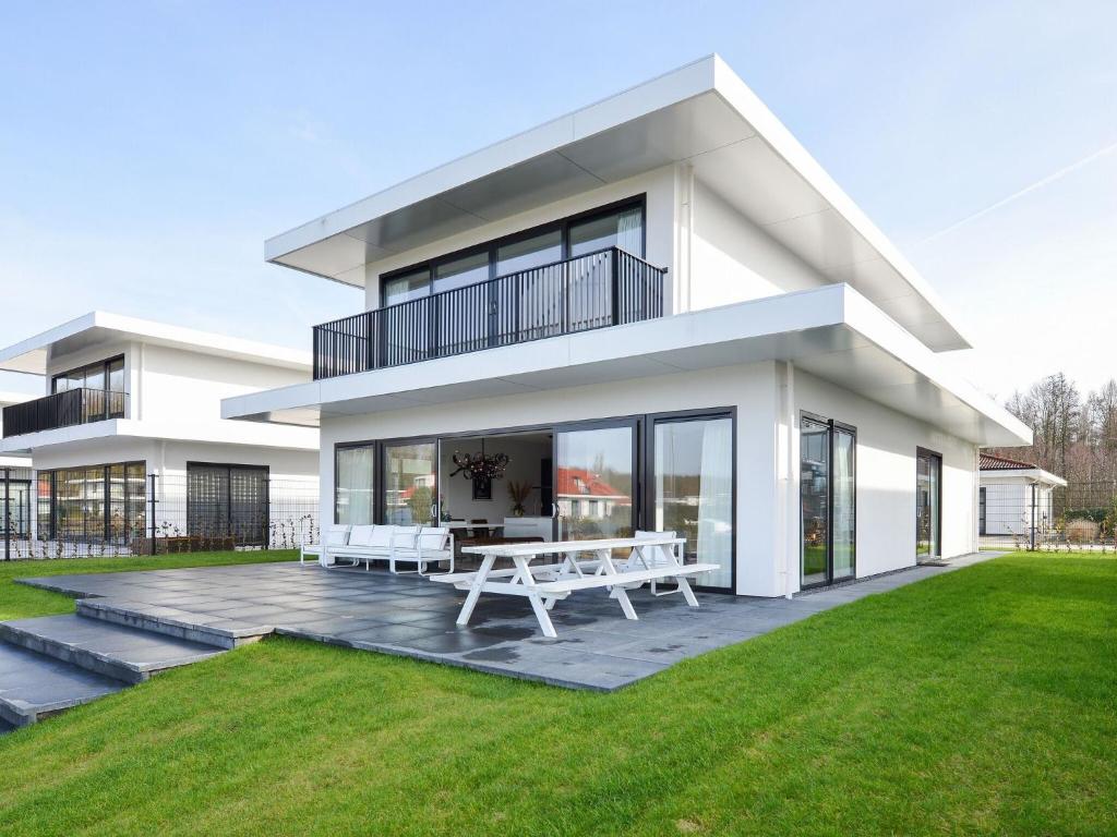 a large white house with a lawn in front of it at Luxury villa on the waterfront with jetty in Zeewolde