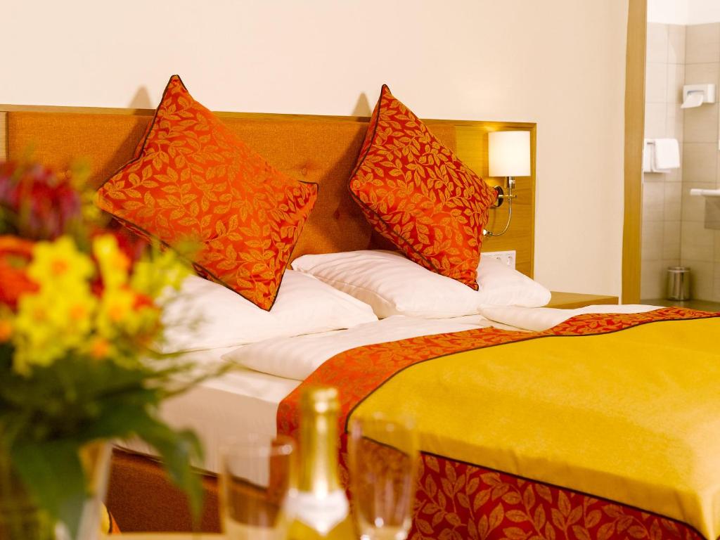 a hotel room with a bed with orange pillows at Hotel Drei Raben in Graz