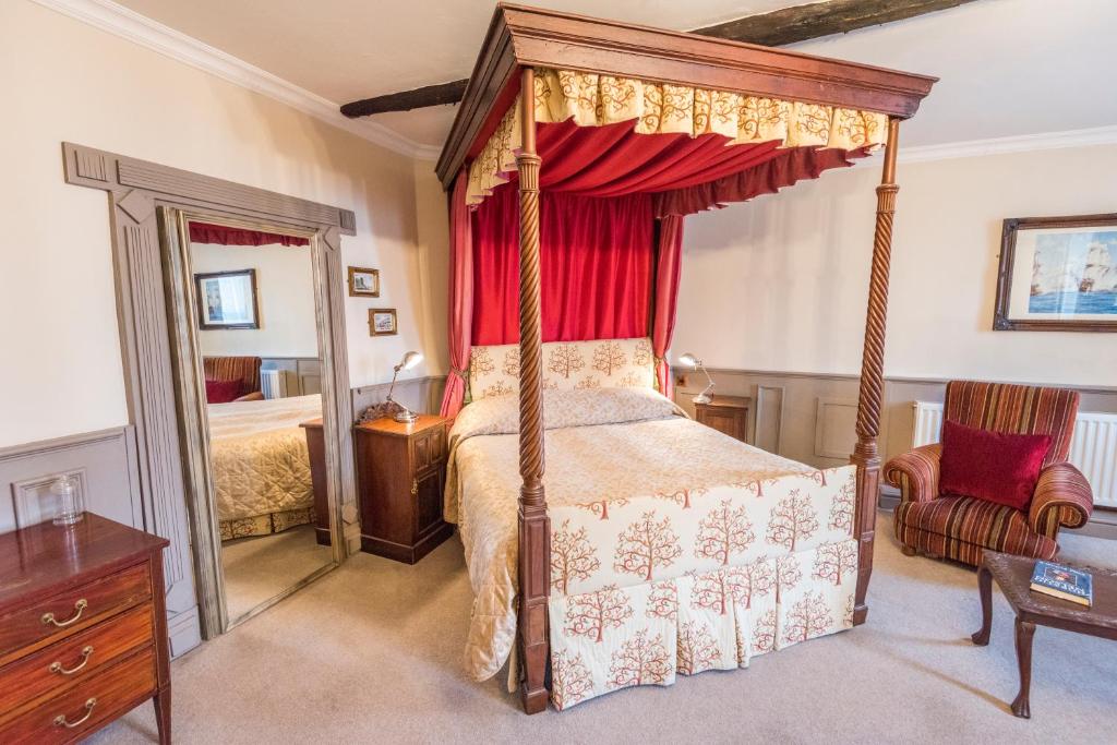 1 dormitorio con cama con dosel y cortina roja en The Castle Hotel, en Llandovery