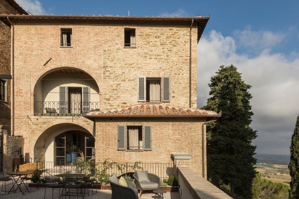 - un grand bâtiment en briques avec une table et des chaises dans l'établissement Rastrello, à Panicale