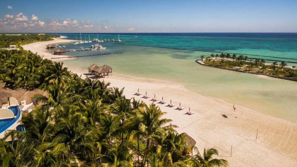 una playa con palmeras y barcos en el agua en El Dorado Maroma A Spa Resort - More Inclusive, en Playa del Carmen