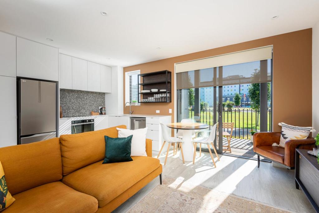 uma sala de estar com um sofá e uma cozinha com uma mesa em The Nest Central Christchurch em Christchurch