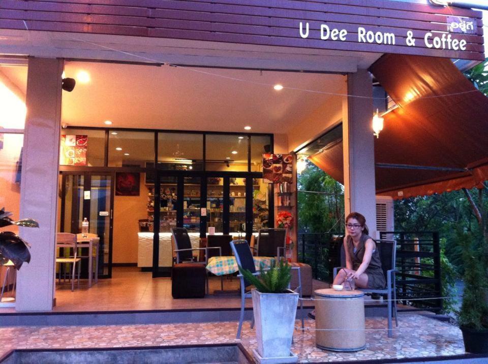 a woman sitting at a table outside of a restaurant at U Dee Room and Coffee in Kanchanaburi City