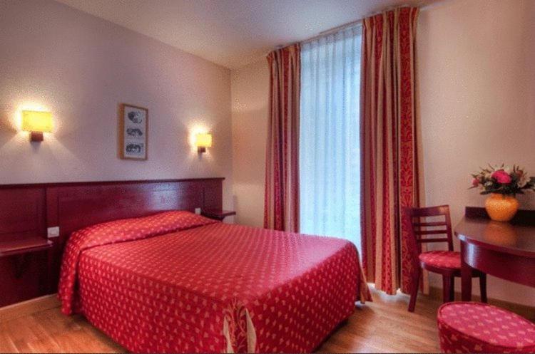 Habitación de hotel con cama roja y escritorio. en Hôtel De Paris Opera, en París