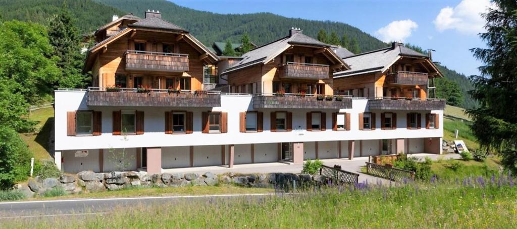 une grande maison sur une colline avec des montagnes en arrière-plan dans l'établissement Appartement Kaiserhof, à Bad Kleinkirchheim