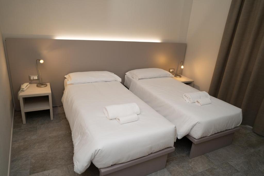 ドッソブオノにあるHotel Europaのホテルルーム ベッド2台 白いシーツ付