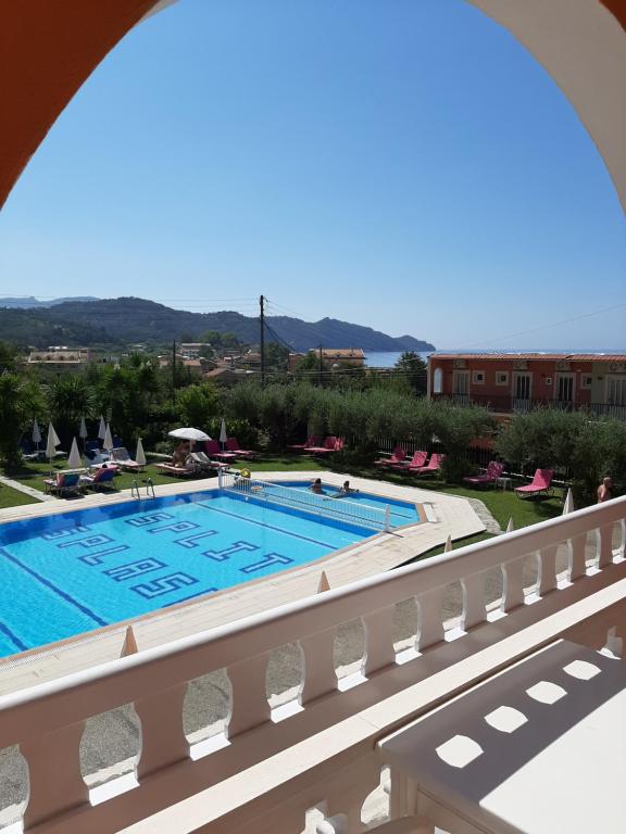 a swimming pool with a balcony overlooking the ocean at Eleni Apartments in Arillas