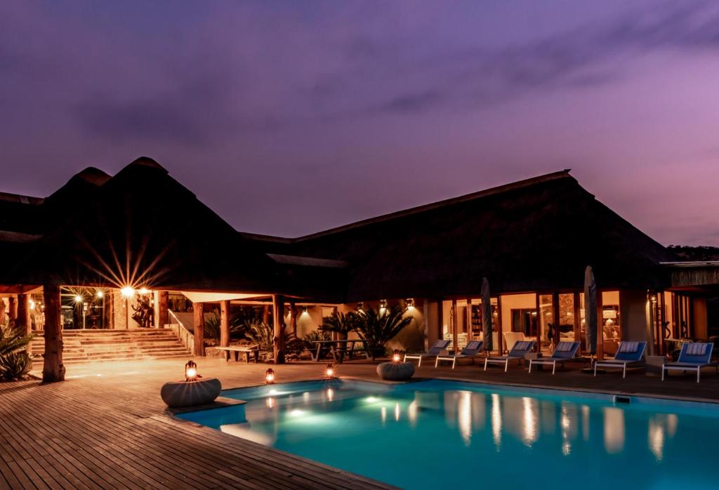 a villa with a swimming pool at night at Lions Valley Lodge in Nambiti Private Game Reserve