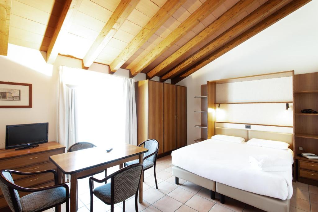 una camera con letto, tavolo e sedie di Residenza Le Cupole a Parma