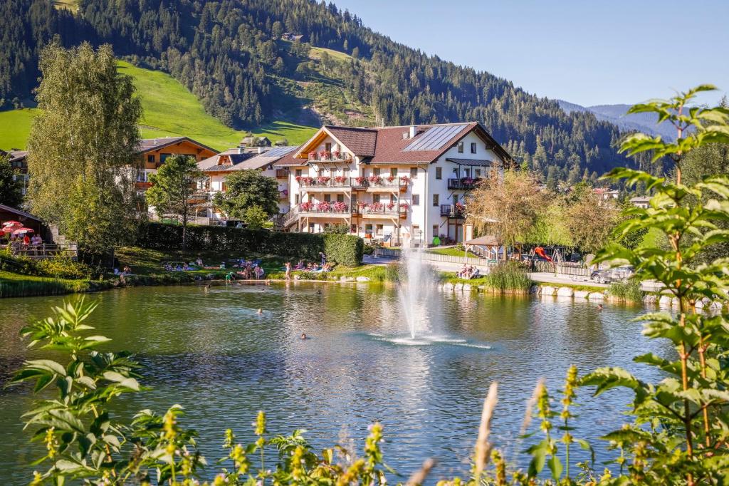 a town in the mountains with a lake and a fountain at Aparthotel am Reitecksee in Flachau