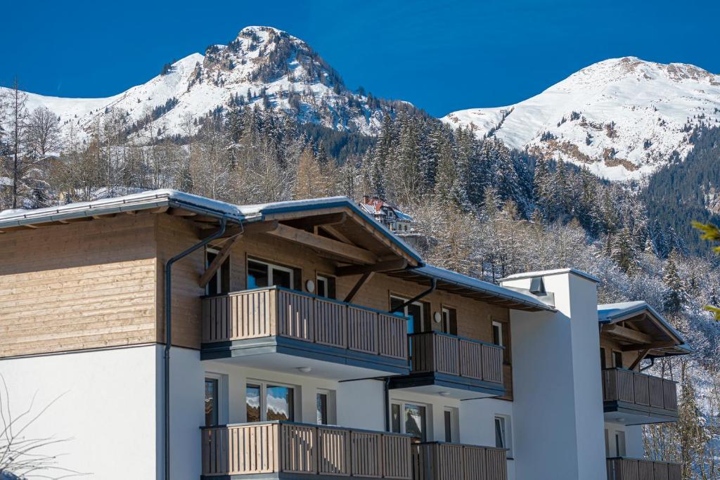 a building with snow covered mountains in the background at Haus Bergblick by AlpenTravel in Bad Hofgastein