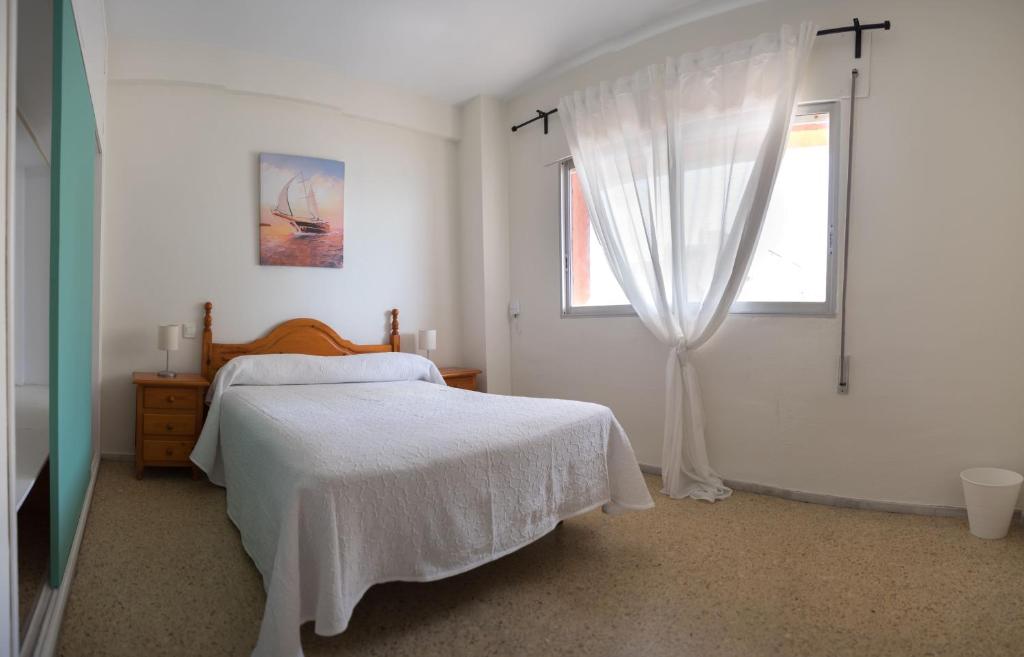 een witte slaapkamer met een bed en een raam bij Delfín Playa Basic Ha Apartment in Cádiz