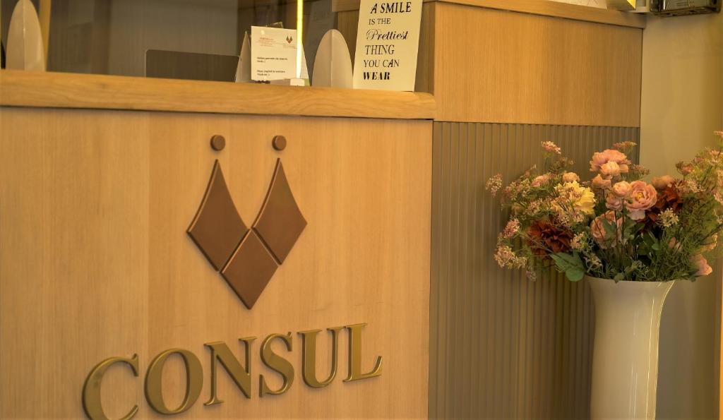 a reception desk with a vase of flowers on it at Hotel Consul in Split