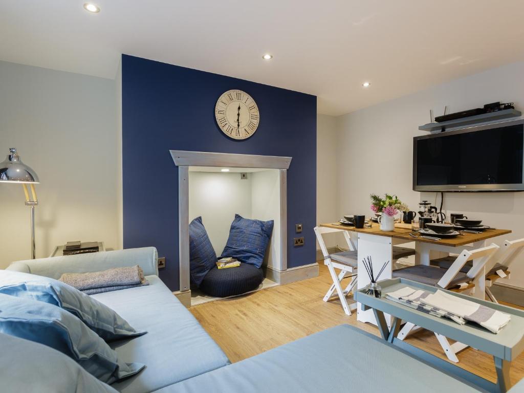 a living room with a blue wall with a clock at Stopover at ALBANY GARDEN APARTMENT with great outdoor space in Portsmouth