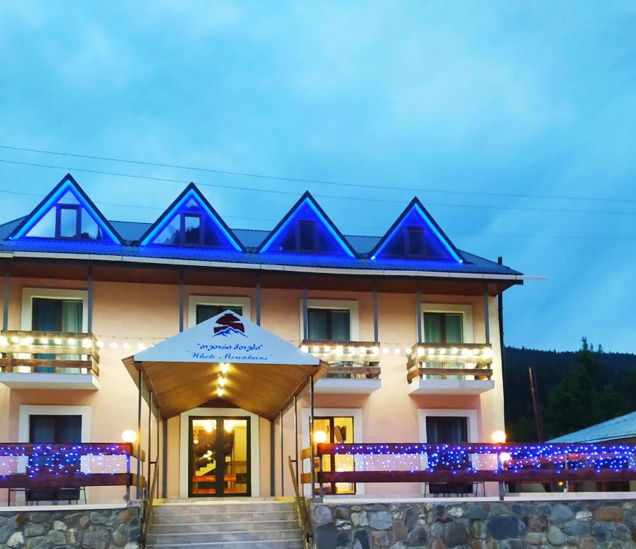- un grand bâtiment avec des lumières bleues dans l'établissement Hotel White Mountains • თეთრი მთები, à Mestia