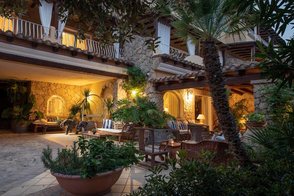 a courtyard of a building with chairs and a palm tree at Boutique Hotel Su Sergenti in Villasimius