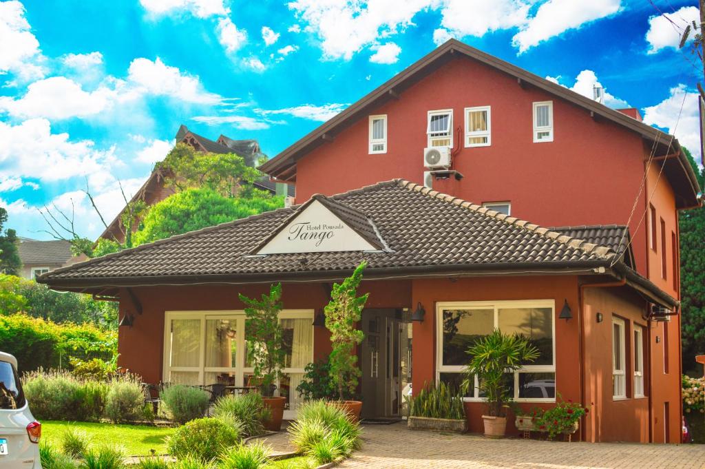 Ein rotes Haus mit einem Schild drauf. in der Unterkunft Pousada Tango in Gramado