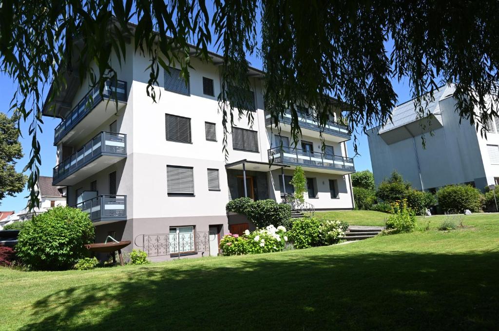 沃爾特湖畔韋爾登的住宿－Villa Berginz by Seebnb，白色的公寓楼,设有绿色庭院